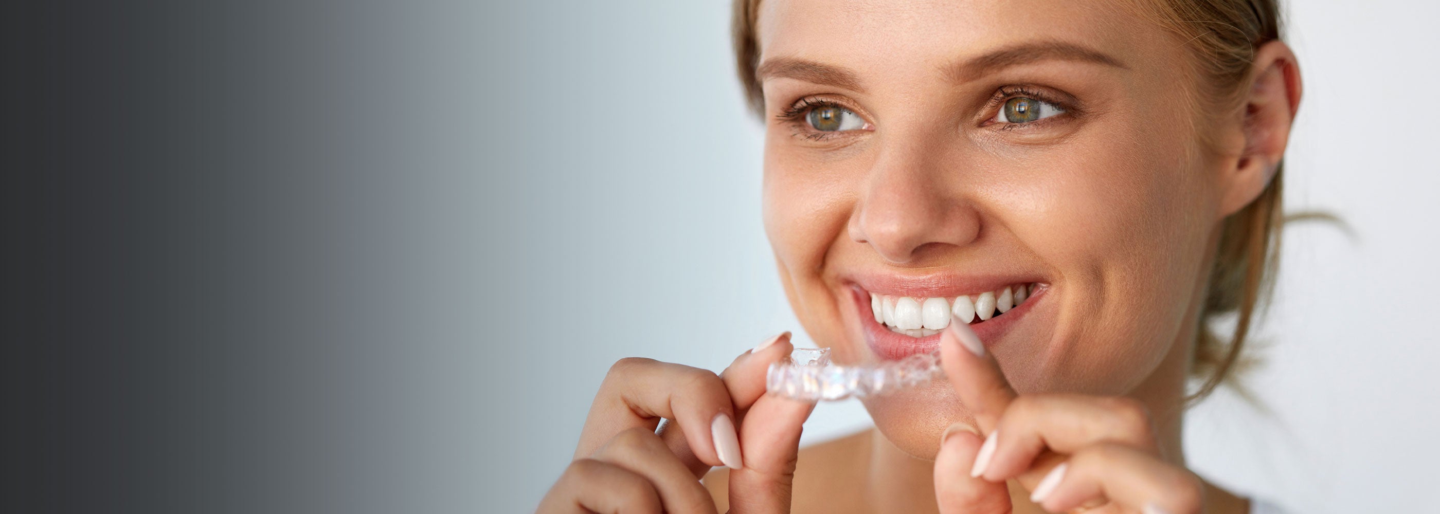 Lady holding a clear aligner for teeth straightening