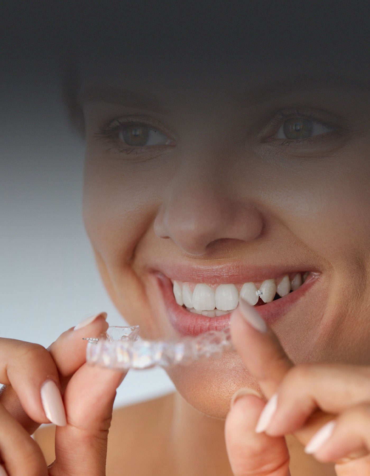 Lady holding a clear aligner for teeth straightening
